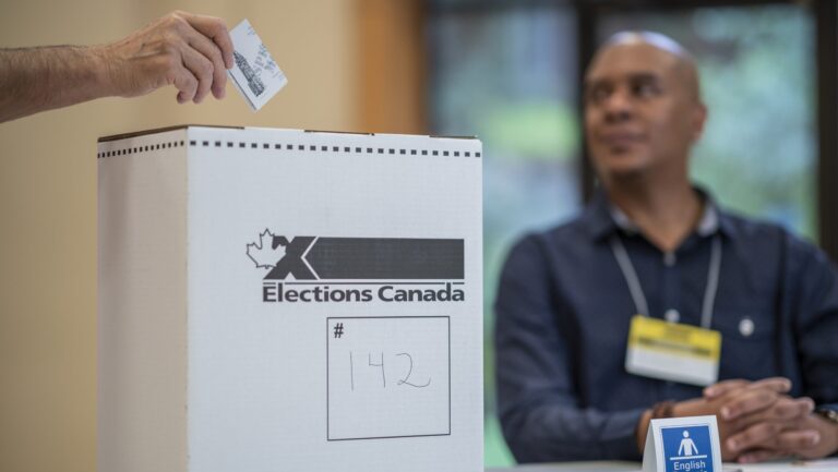 An elector casting a ballot at an Elections Canada box